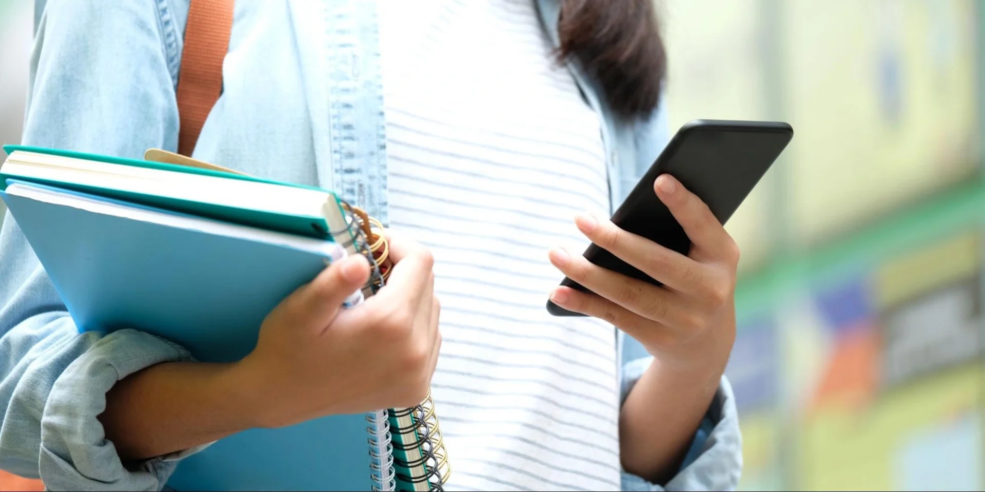 Veterinary medicine student holding books and using a smartphone for academic resources, supported by Vetucore LLC.