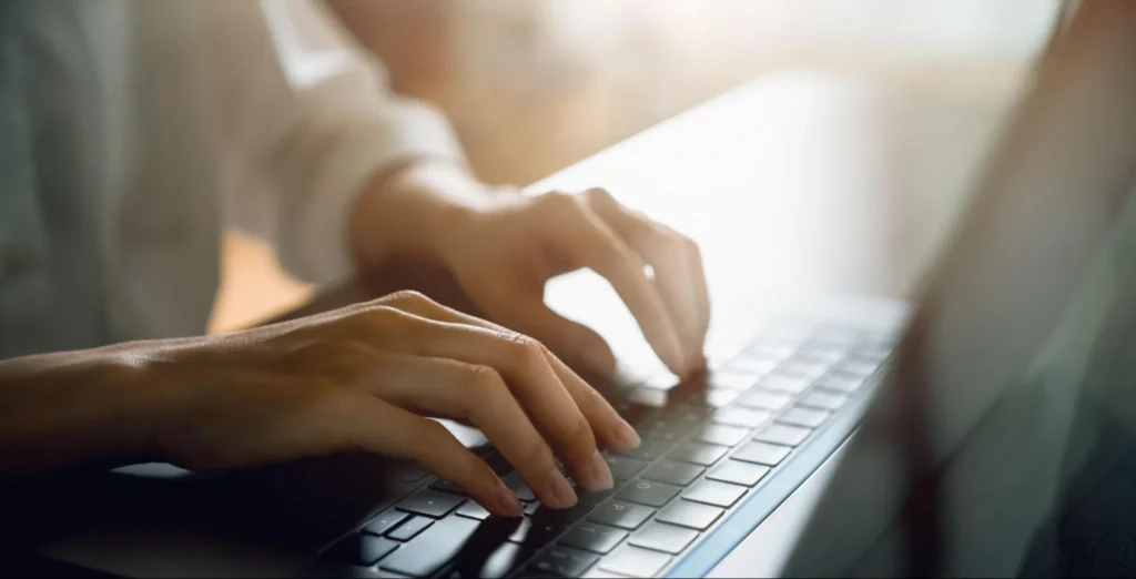 Close-up of hands typing on a laptop, representing online applications for veterinary medicine schools.