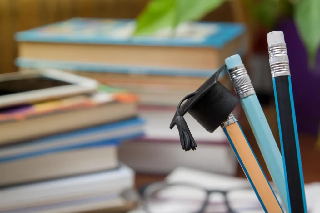 Pencils with a graduation cap beside stacks of books and a tablet, symbolizing academic success and veterinary medicine degree preparation – Vetucore LLC.