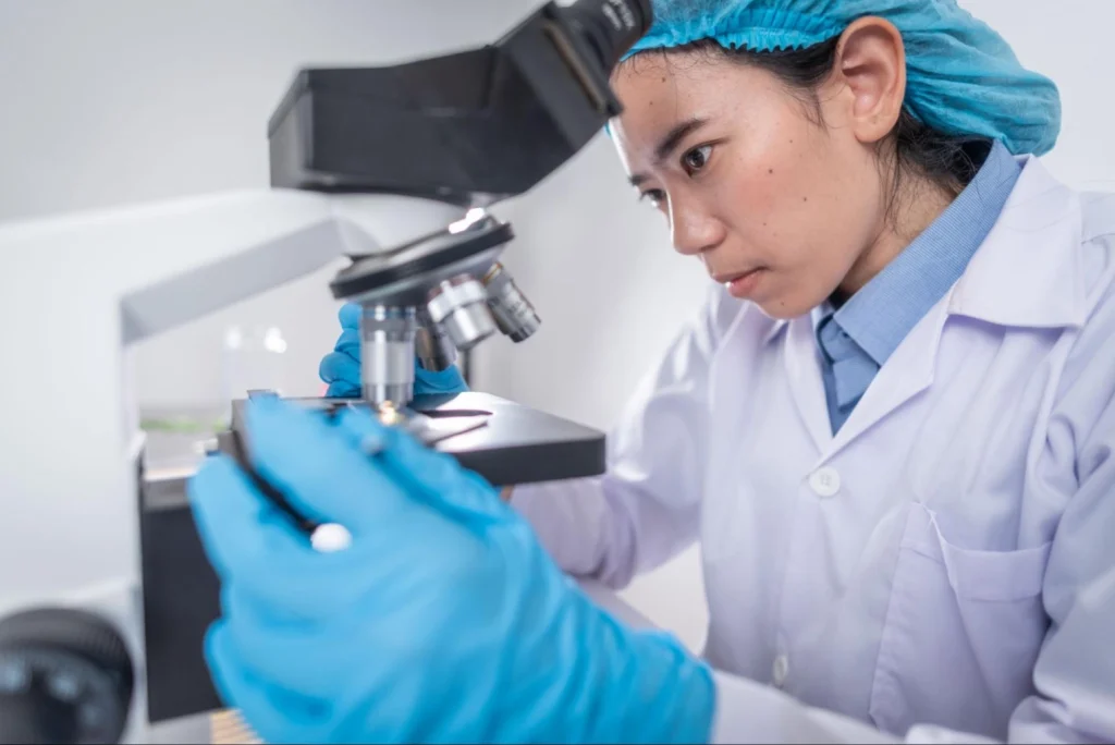 Focused veterinary student in lab coat using microscope for research — Vetucore LLC supports your veterinary medicine degree journey. 